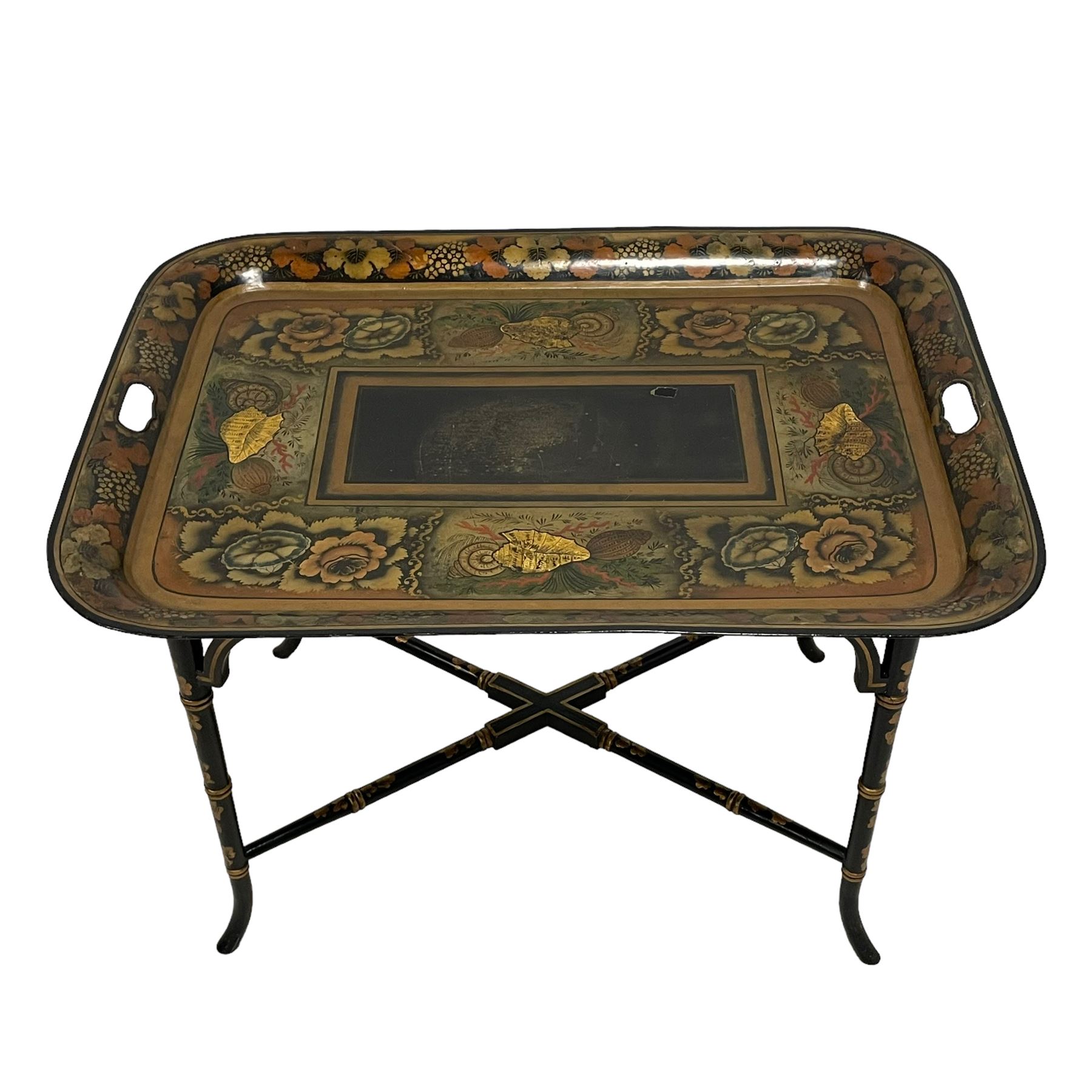 19th century tole ware tray of rectangular form, decorated with Japanese inspired floral motifs and gilt shells, with pierced handles, the associated ebonised and gilt stand, raised on ring turned splayed supports united by X-stretcher, decorated with gilt foliage