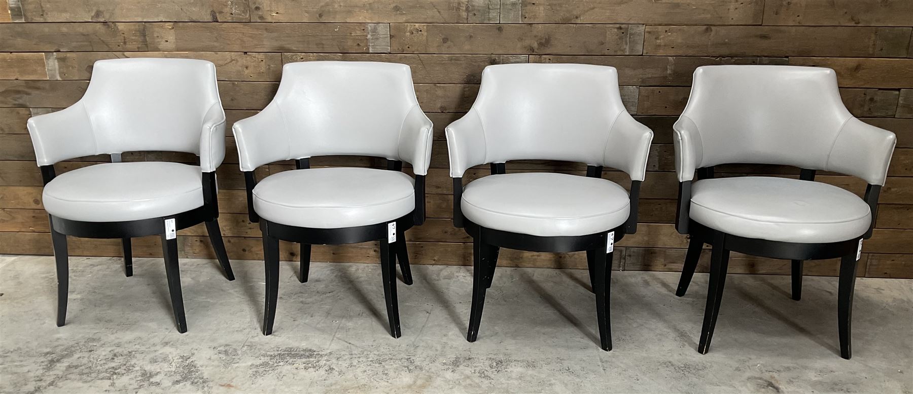 Four ebonised framed tub shaped armchairs, upholstered in grey fabric