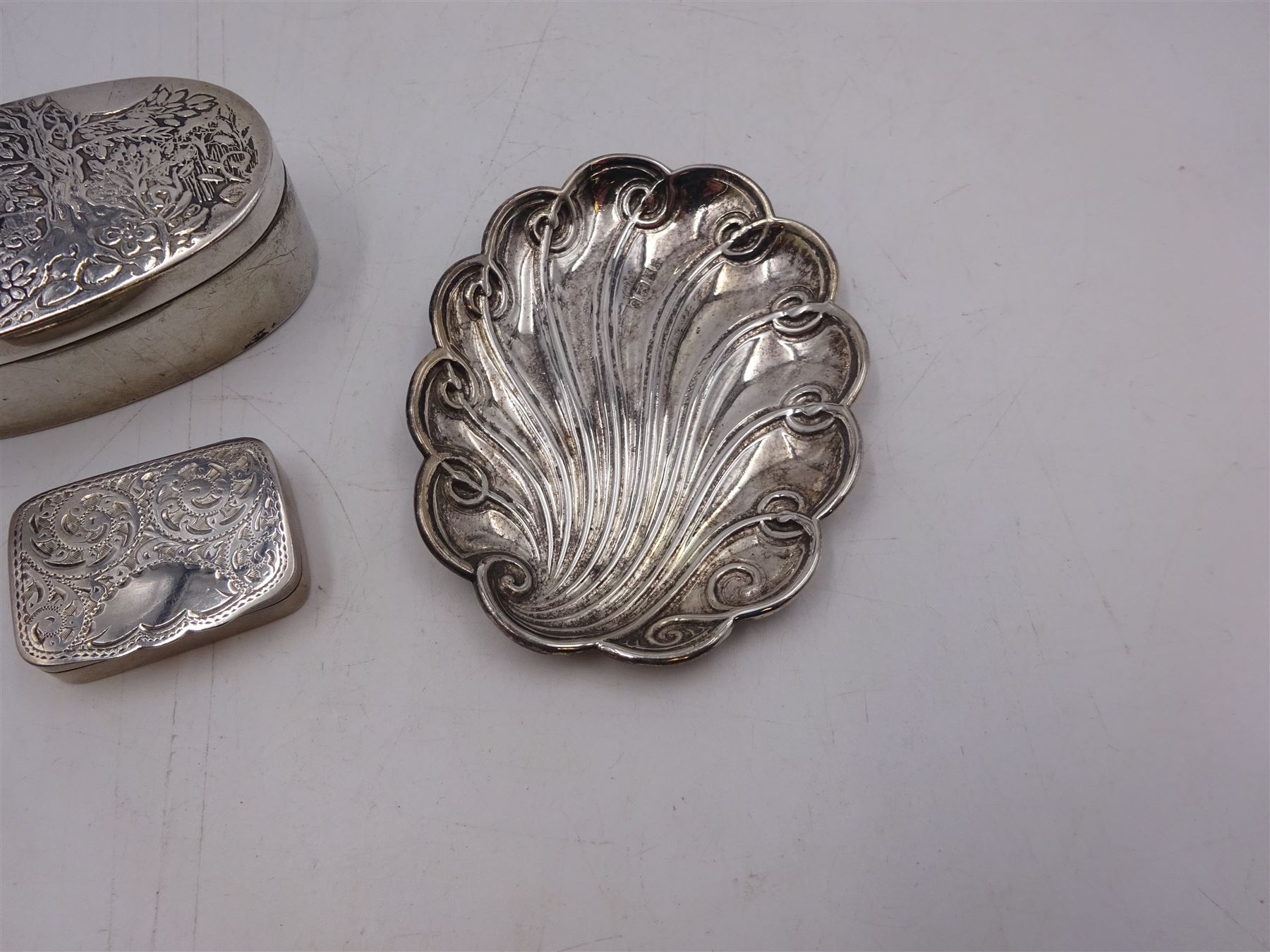 Modern silver oval box, decorated to the removable cover with an owl on a branch, hallmarked London 1984, makers mark KB, together with a modern silver pin tray of scrolling lobed form, hallmarked 1992, makers mark EM, and an early 20th century silver pill box, hallmarked Adie & Lovekin Ltd, Birmingham 1910, oval box H2.2cm, W6.5cm