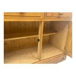 Large traditional pine dresser, shaped cornice over three open shelves, base fitted with four drawers above four panelled cupboards, each with turned wooden knobs, on plinth base