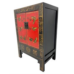 20th century Chinese black lacquered cabinet, rectangular body with two doors enclosing single shelf interior, adorned with gilt butterfly and floral motifs against a red backdrop, standing on square supports