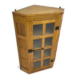 Rabbitman - oak corner cabinet, astragal glazed door enclosing three internal shelves, panelled upright corners, fitted with wrought metal hinges and latch, carved with rabbit signature, by Peter Heap, Wetwang 