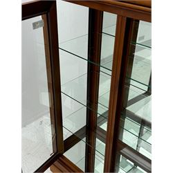 20th century cherry wood display cabinet, projecting cornice over two glazed doors with bevelled panes flanked by fluted support columns, enclosing three adjustable glass shelves with mirror-back surface, supported by shaped bracket feet