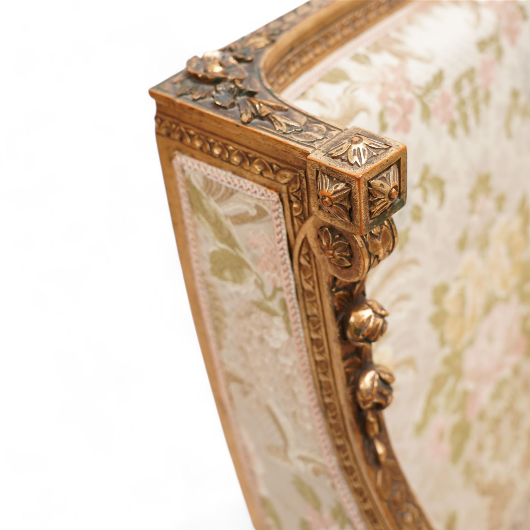 Late 19th century French gilt wood and gesso enclosed armchair, the cresting carved with floral bouquets over foliate moulding, upholstered in floral pattern fabric with repeating pattern, down-swept arms with scrolled acanthus leaf terminals, on turned and fluted feet carved with foliage 