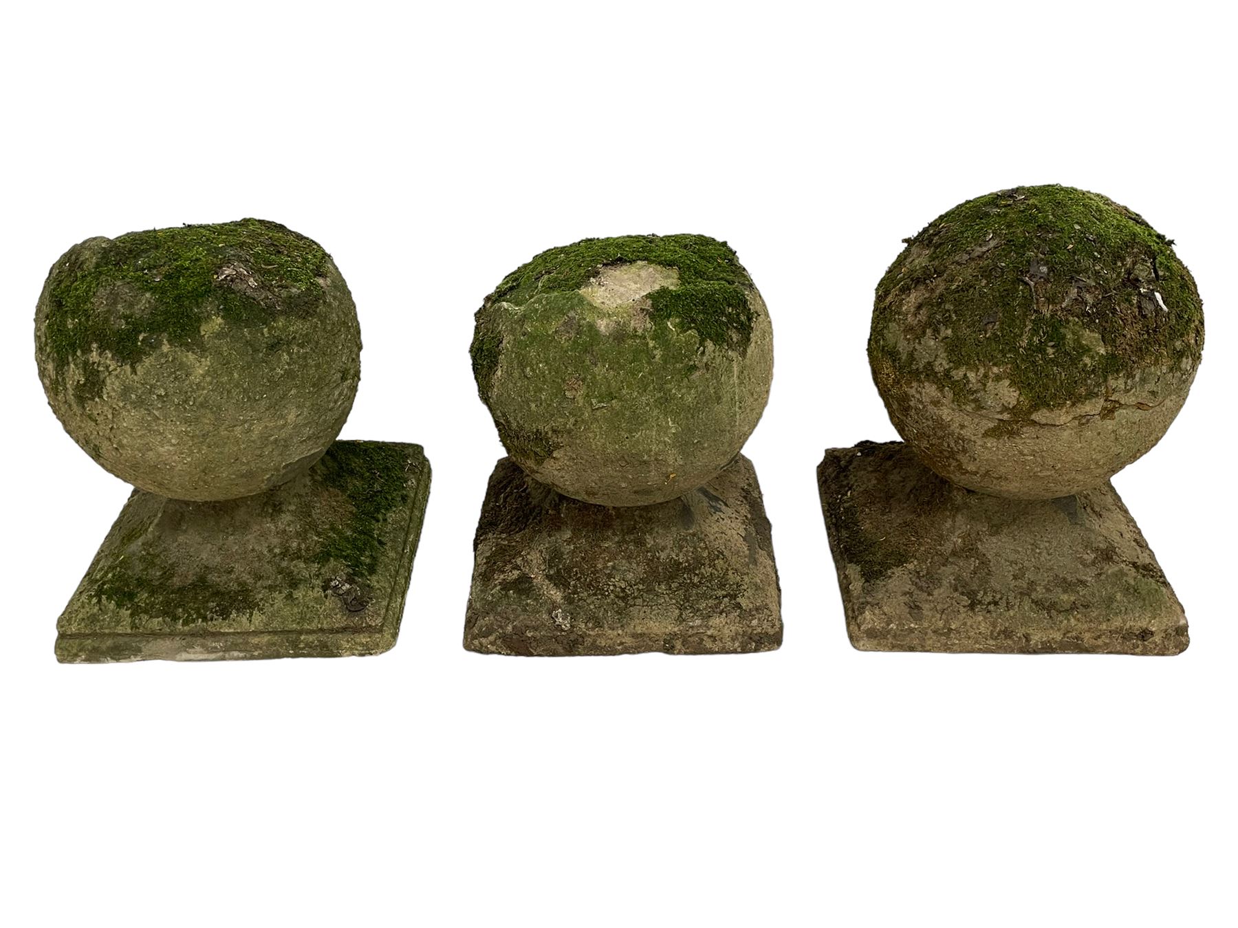 Set of three weathered cast stone gate post finials, circular orb on step-canted square base 