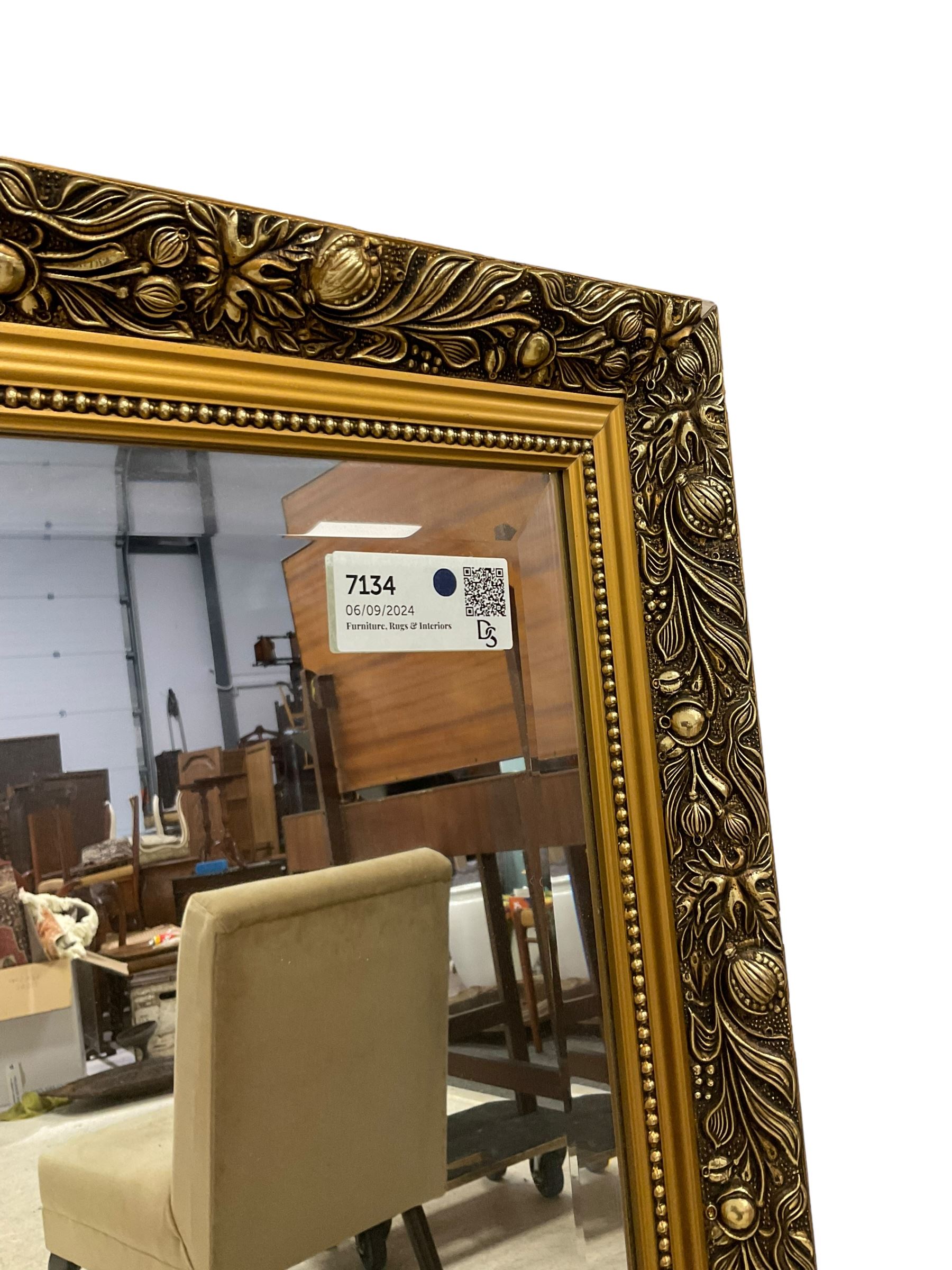 Large rectangular gilt framed wall mirror, decorated with trailing leafy branches and flowerheads, bevelled glass plate 