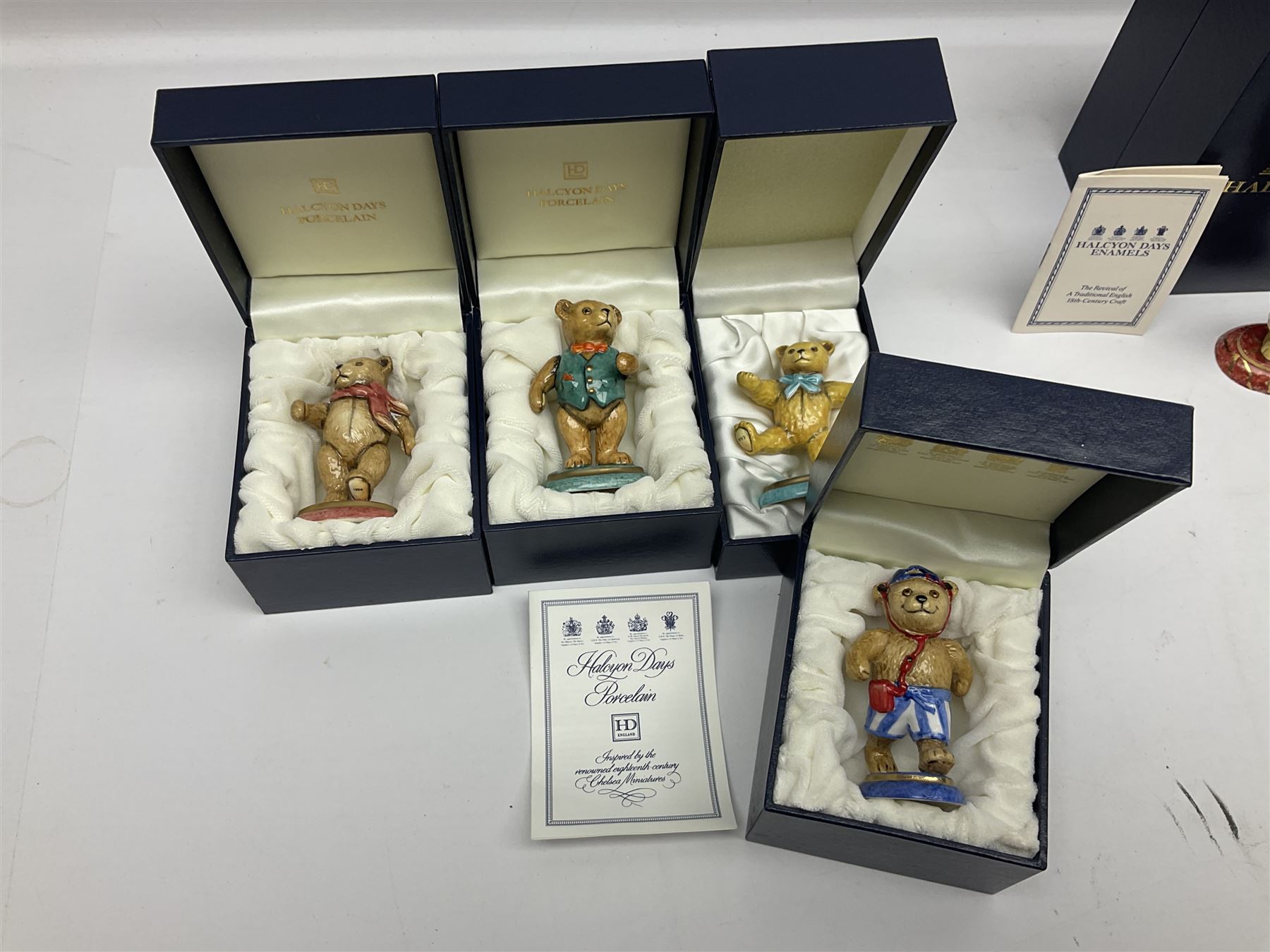 Eight Halcyon Days Teddy Bear of the Year figures, from 1993 to 2000, including one example modelled as a bear in Greek dress carrying a torch, one example modelled as a schoolboy and one example in a blue dress, all boxed 