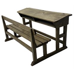 Victorian child's pine double school desk, the writing surface with two inkwells and two shelves underneath, integrated slatted bench seat raised on supports united by stretcher 