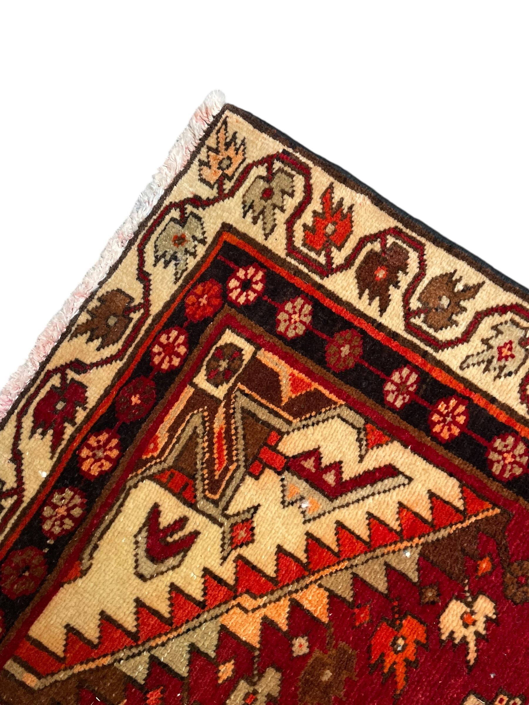 Persian crimson ground rug, the field decorated with three medallions within stepped borders, decorated all over with small stylised plant motifs, trailing flower head outer band and floral pattern border 