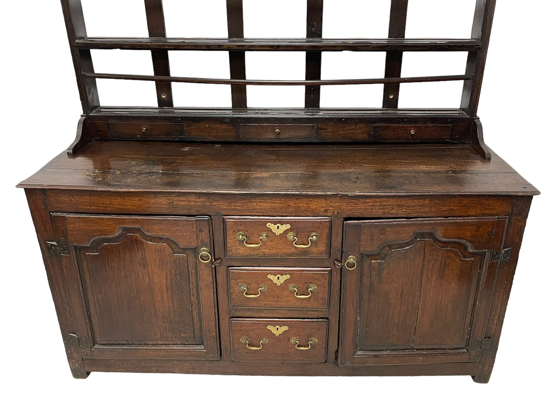 18th century oak dresser, projecting cornice over three heights plate rack with three small drawers, rectangular ovolo-moulded top over three central drawers and two flanking cupboards, enclosed by fielded panelled doors, on stile supports 