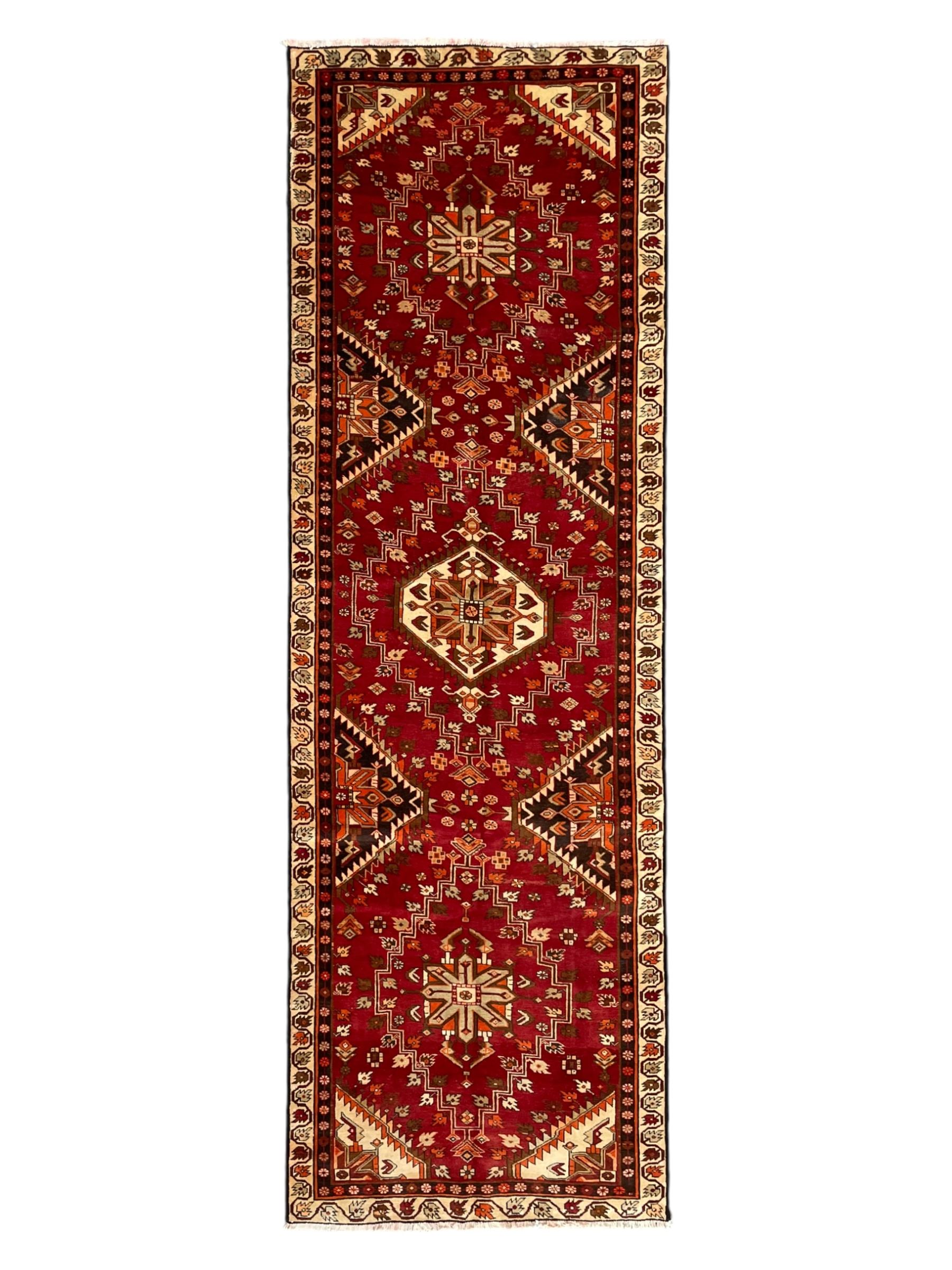 Persian crimson ground rug, the field decorated with three medallions within stepped borders, decorated all over with small stylised plant motifs, trailing flower head outer band and floral pattern border 