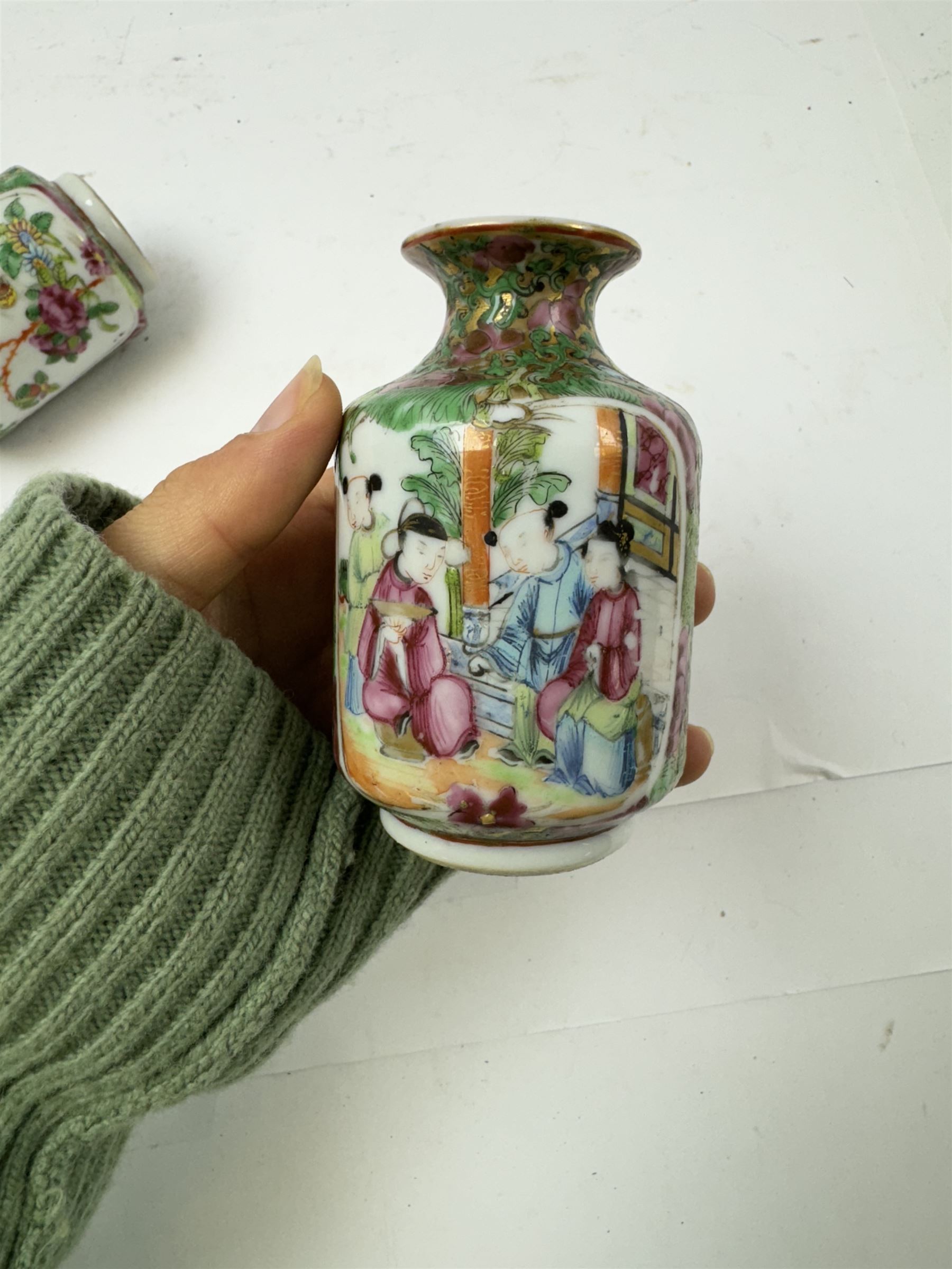 Pair of Chinese famille rose miniature vases, painted with panels depicting figures in a garden, with flora and fauna decoration, H10cm