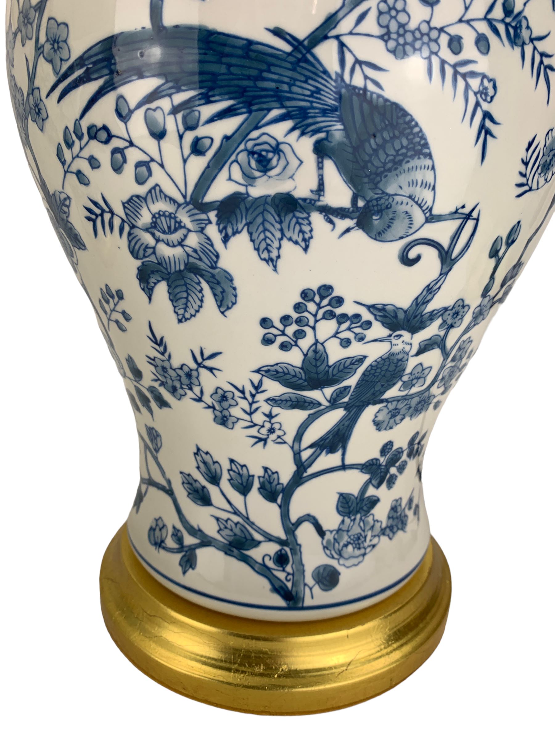 Pair of blue and white table lamps, each of inverted baluster form, decorated with exotic birds, raised upon circular gilt bases, H39cm excluding fitting