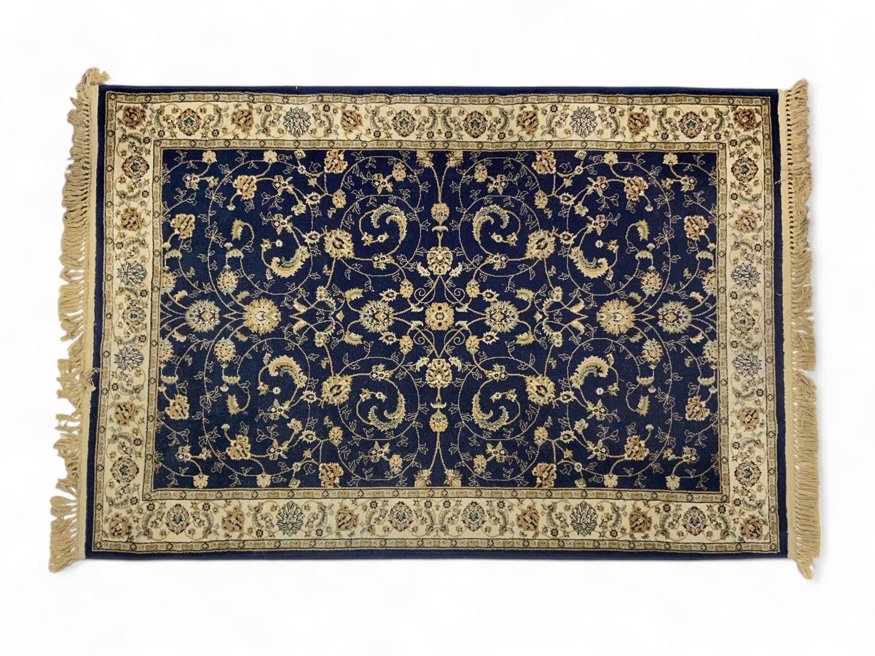 Afghan Bokhara rust ground rug, decorated with three columns of Gul motifs, the wide guard band with further scrolling and geometric designs (183cm x 129cm); together with a Persian design indigo ground rug (W170cm x 117cm)