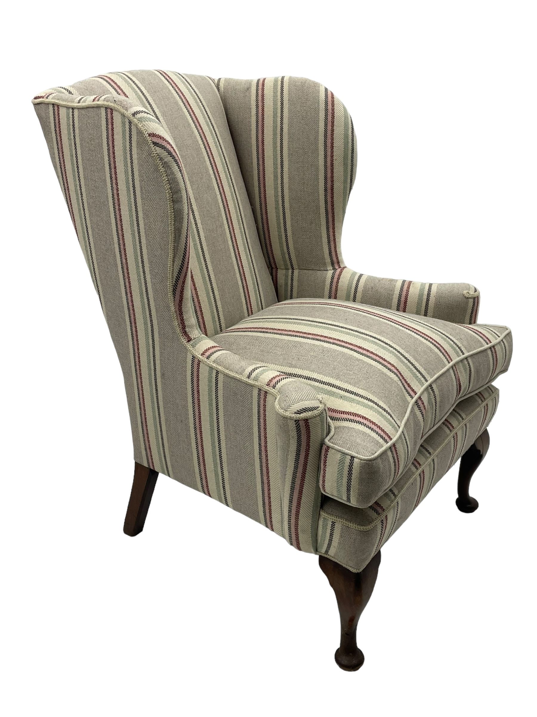 Georgian design hardwood-framed wingback armchair, curved wingback terminating to curved and rolled arms, upholstered in striped fabric with loose seat cushion, on cabriole front feet 