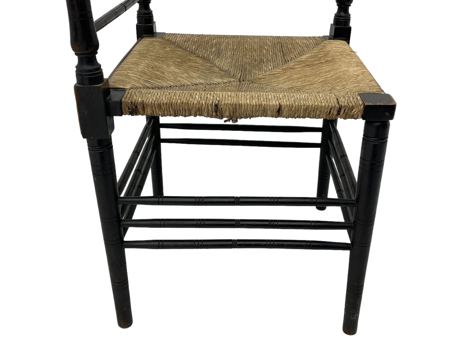 In the manner of William Morris - Arts & Crafts period corner chair, swell turned horizontal rails with balustrade back, rush seat on ring turned supports, black paint finish 