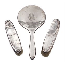 Early 20th century three piece silver mounted dressing table set, comprising hand mirror and two clothes brushes, each with engraved monogram, hallmarked Wilmot Manufacturing Co, Birmingham 1918