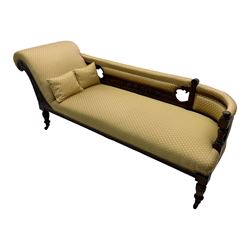 Late Victorian walnut framed chaise longue, scrolled backrest and sides upholstered in patterned yellow fabric, carved floral motifs to the backrest and sides, raised on turned supports with castors