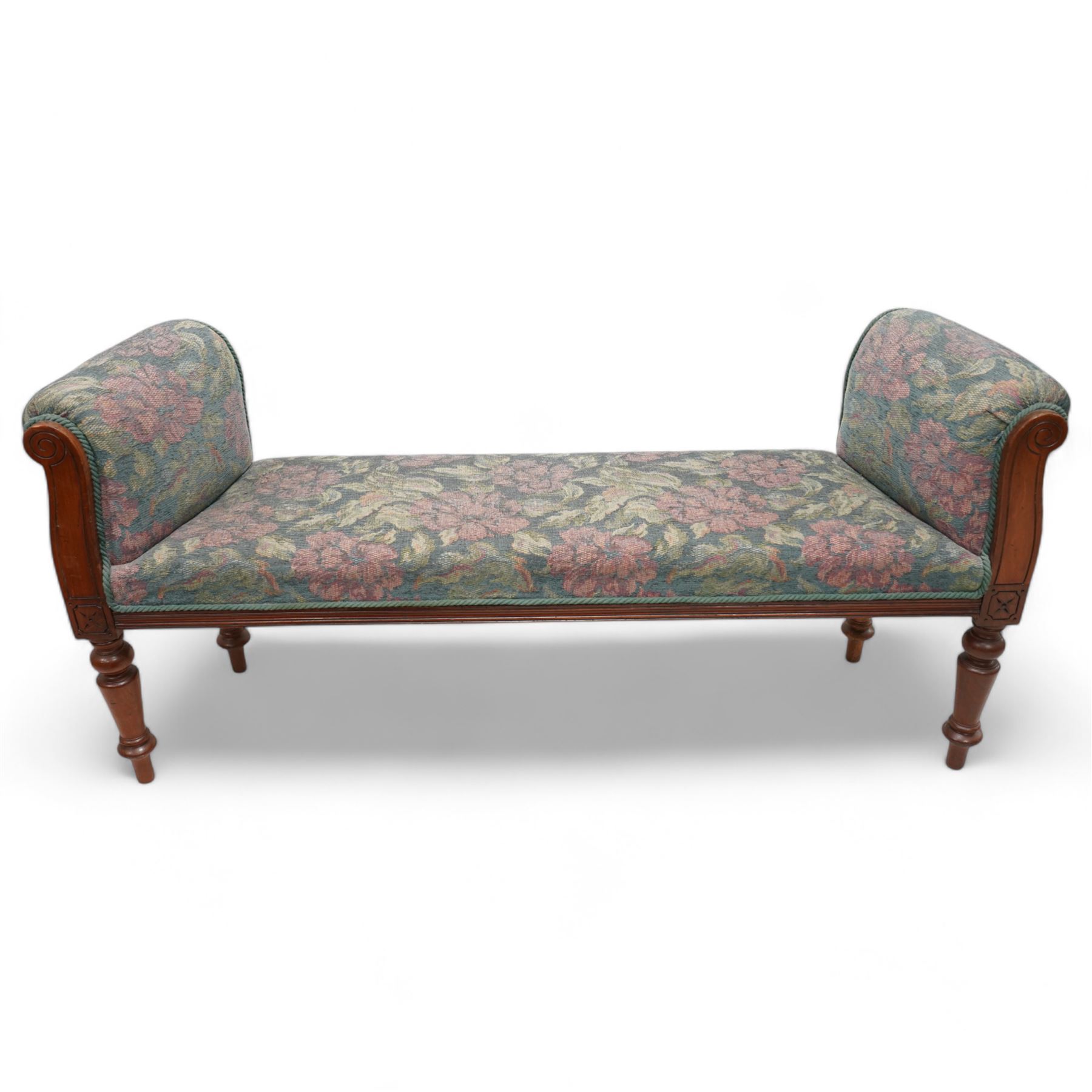 19th century mahogany framed bay window seat of tapered form, rolled arms decorated with carved scrolling, seat and arms upholstered in indigo ground floral patterned fabric, moulded lower rail over turned supports