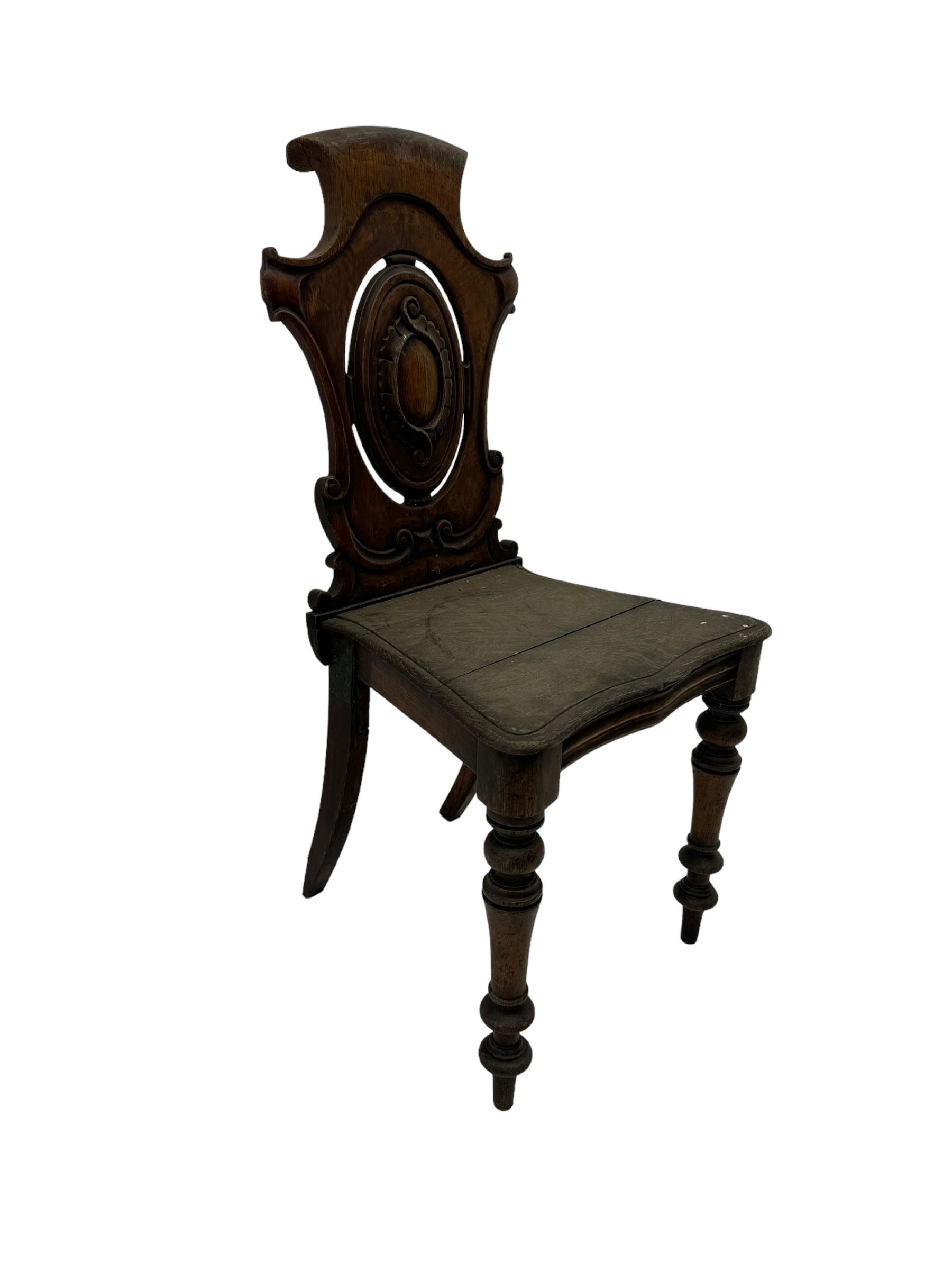 Victorian oak hall chair with scroll carved and pierced back, shaped seat and turned front supports