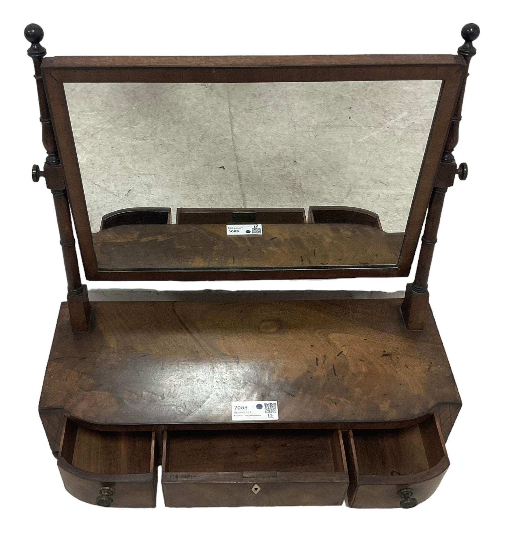 George III mahogany toilet mirror, rectangular plate on ring turned supports with swing action, three drawers with simulated ivory escutcheon, on ebonised bun feet