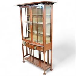 Edwardian mahogany glazed display cabinet, projecting cornice over astragal glazed doors enclosing three velvet lined shelves, over two bow-front drawers with Tunbridge Ware style inlaid stringing, on pierced end supports united by undertier