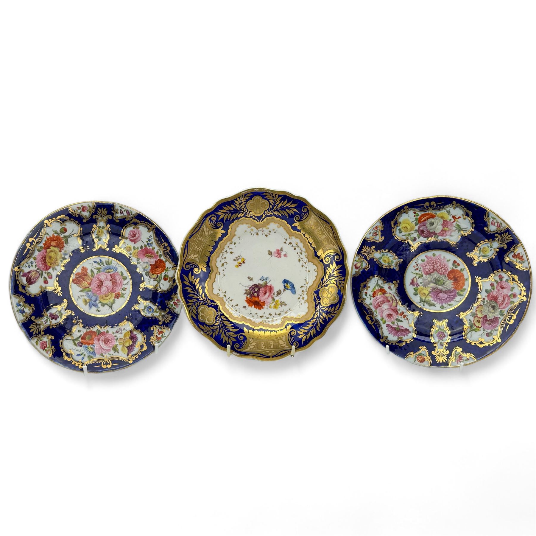 Pair of early 19th century plates, each painted with summer flowers within gilt fan shaped reserves, against a blue scale ground, unmarked, D19cm, together with a 19th century English porcelain plate, pattern no. 2/1078 (3)