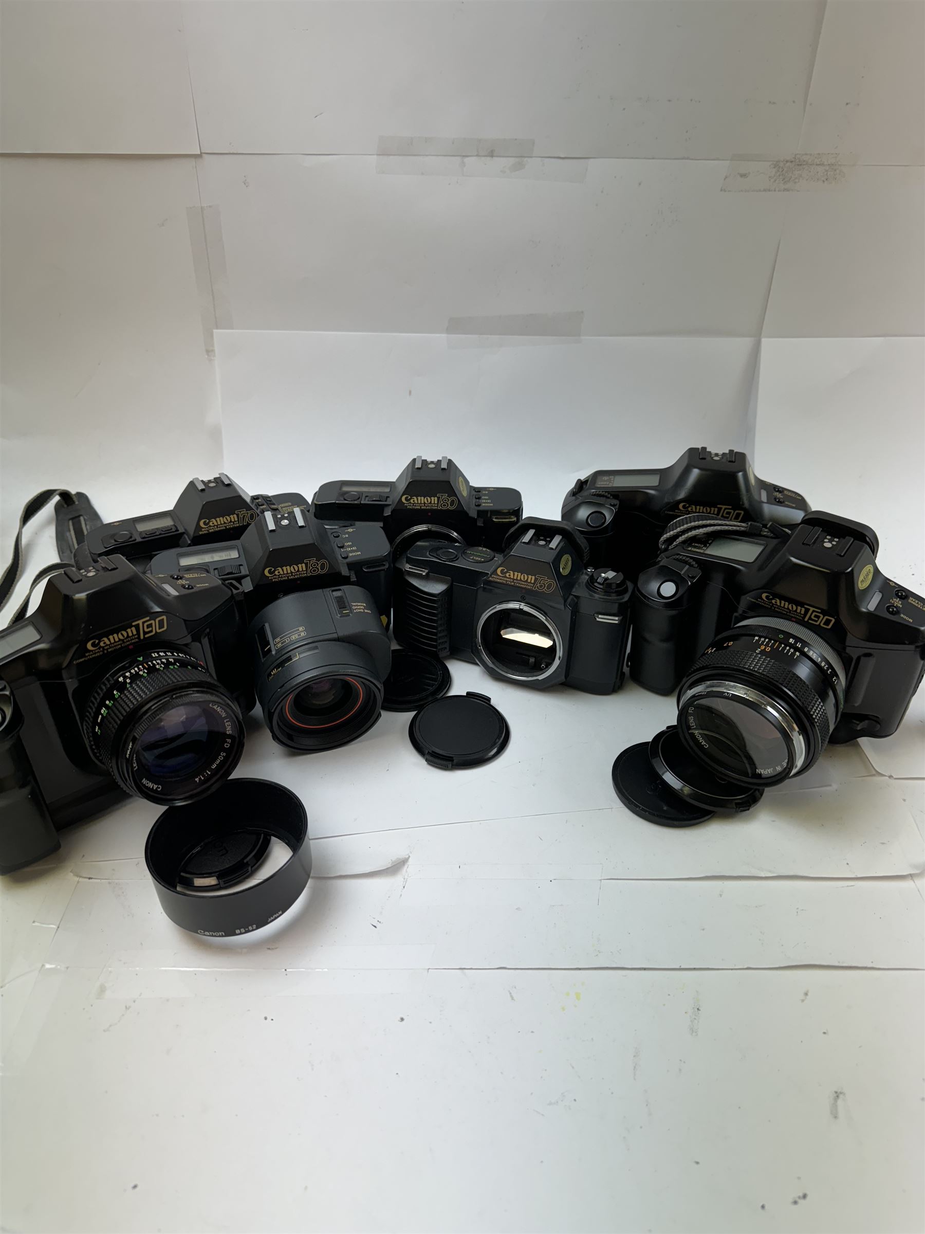 Seven Canon SLR camera bodies, comprising T50 serial no. 2011593, T70 serial no. 1319312, in carry case, two T80 examples, serial nos. 242362 & 256560, one with a Canon AC 35-70mm 1:3.5-4.5 zoom lens, and three T90 examples, serial nos. 1174363, 1005979 & 1019836, one example with a Canon FD 55mm 1:12 lens and one with a Canon FD 50mm 1:1.4 lens, one example with box