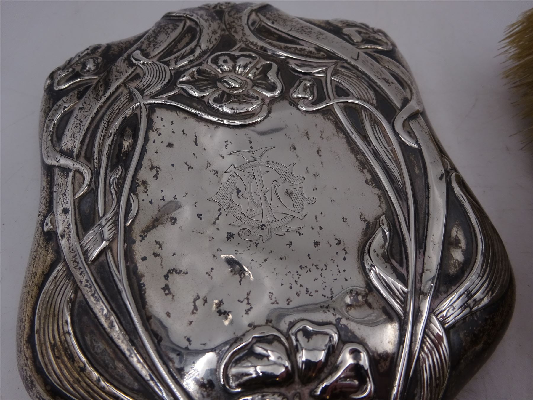 Art Nouveau silver mounted two piece dressing table set, comprising hair brush and hand mirror, each heavily embossed with naturlistic florals and engrved with monograms, hallmarked Walker & Hall, Sheffield 1907