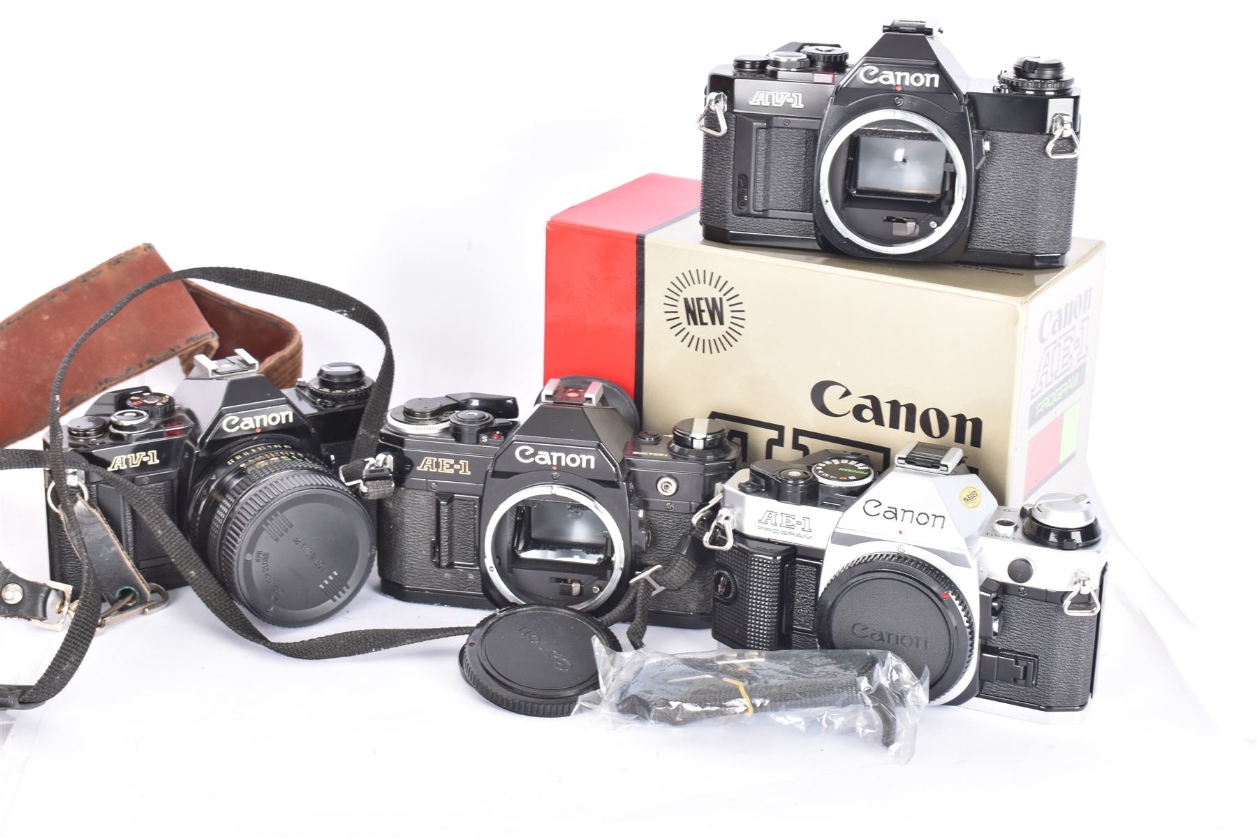 Four Canon SLR camera bodies, to include AE-1 Program, in black and silver finish, serial no. 4330401, boxed, AE-1 serial no. 1234206 and two AV-1 examples, serial nos. 841957 & 334882, one with a Canon FD 50mm 1:18 lens