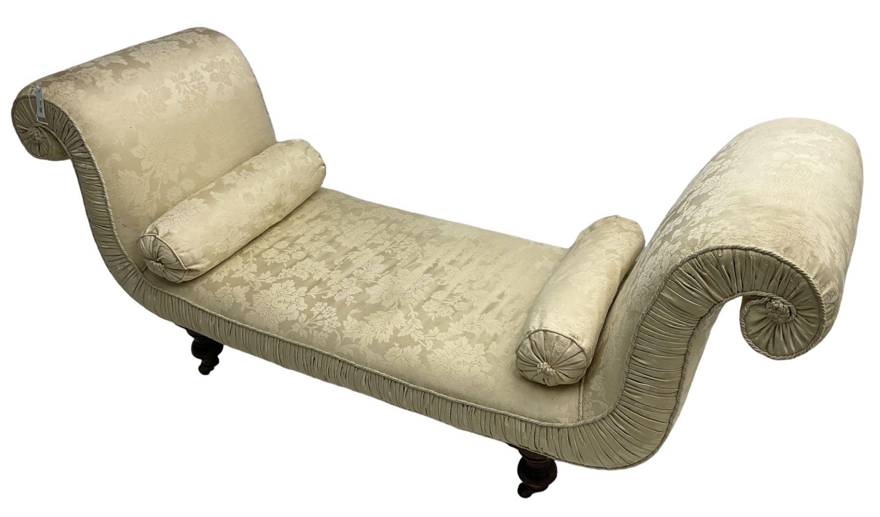 Victorian mahogany framed window seat day bed, the scrolled arms and seat upholstered in ivory foliate patterned damask fabric with matching ropetwist piping, raised on turned supports with castors