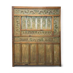 Early 20th century Javanese teak and hardwood door panel or room divider, rectangular panelled form with moulded frame and pegged construction, carved and pierced with scrolling decoration and flower head motifs, shaped and pierced splats with interlocking pattern