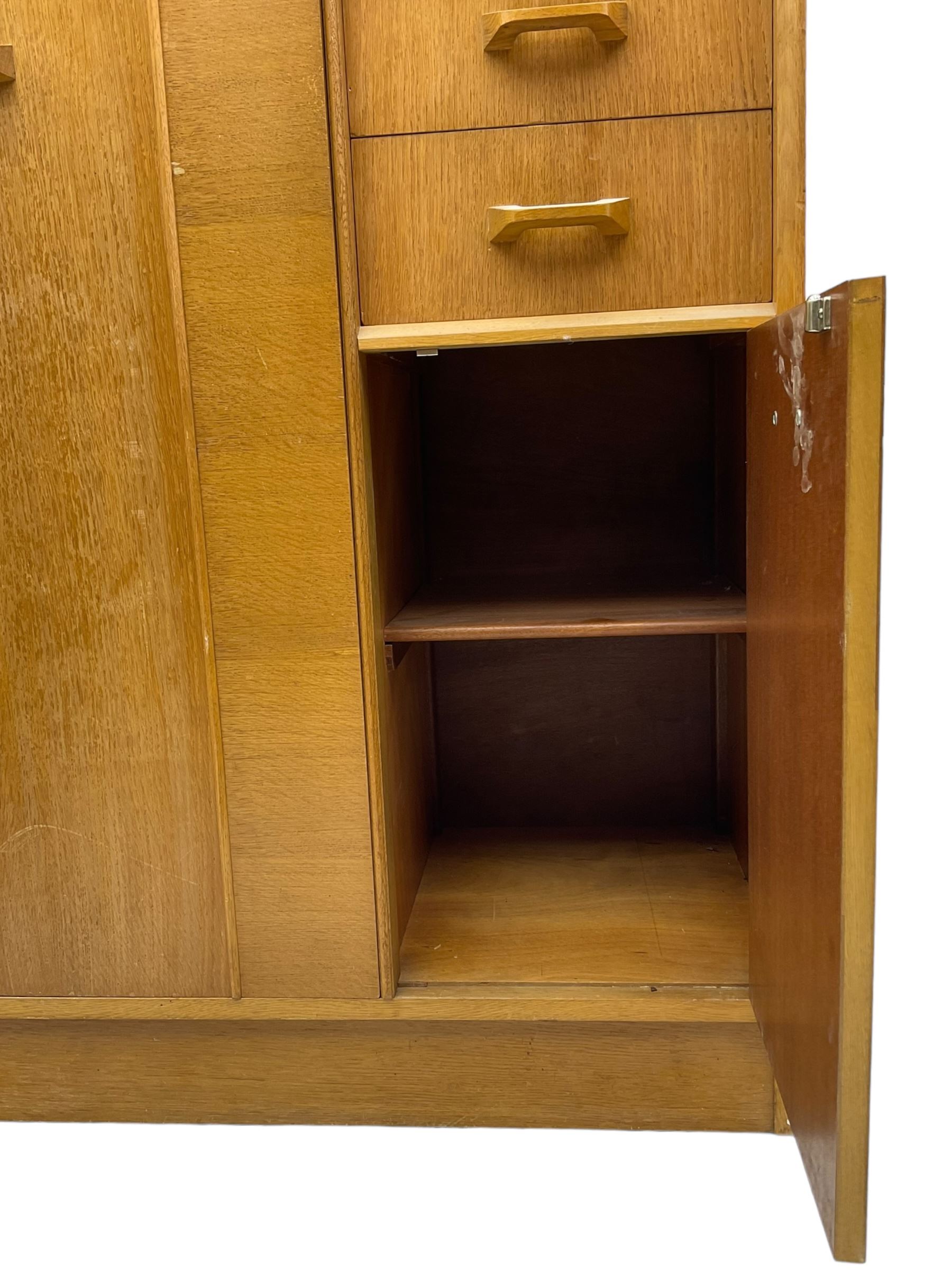 G-Plan - mid 20th century teak tallboy or combination wardrobe, left side with full-height hanging cupboard, right side with three drawers, the top fitted with vanity mirror, above cupboard with shelves, raised on a plinth base