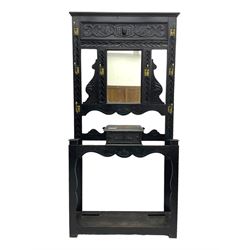 Victorian oak hall stand, the upper section featuring eight brass hooks and central mirror plate flanked by scroll-carved panels, the central section includes a storage box positioned above an umbrella stand, supported by square carved legs with scroll-carved horizontal supports