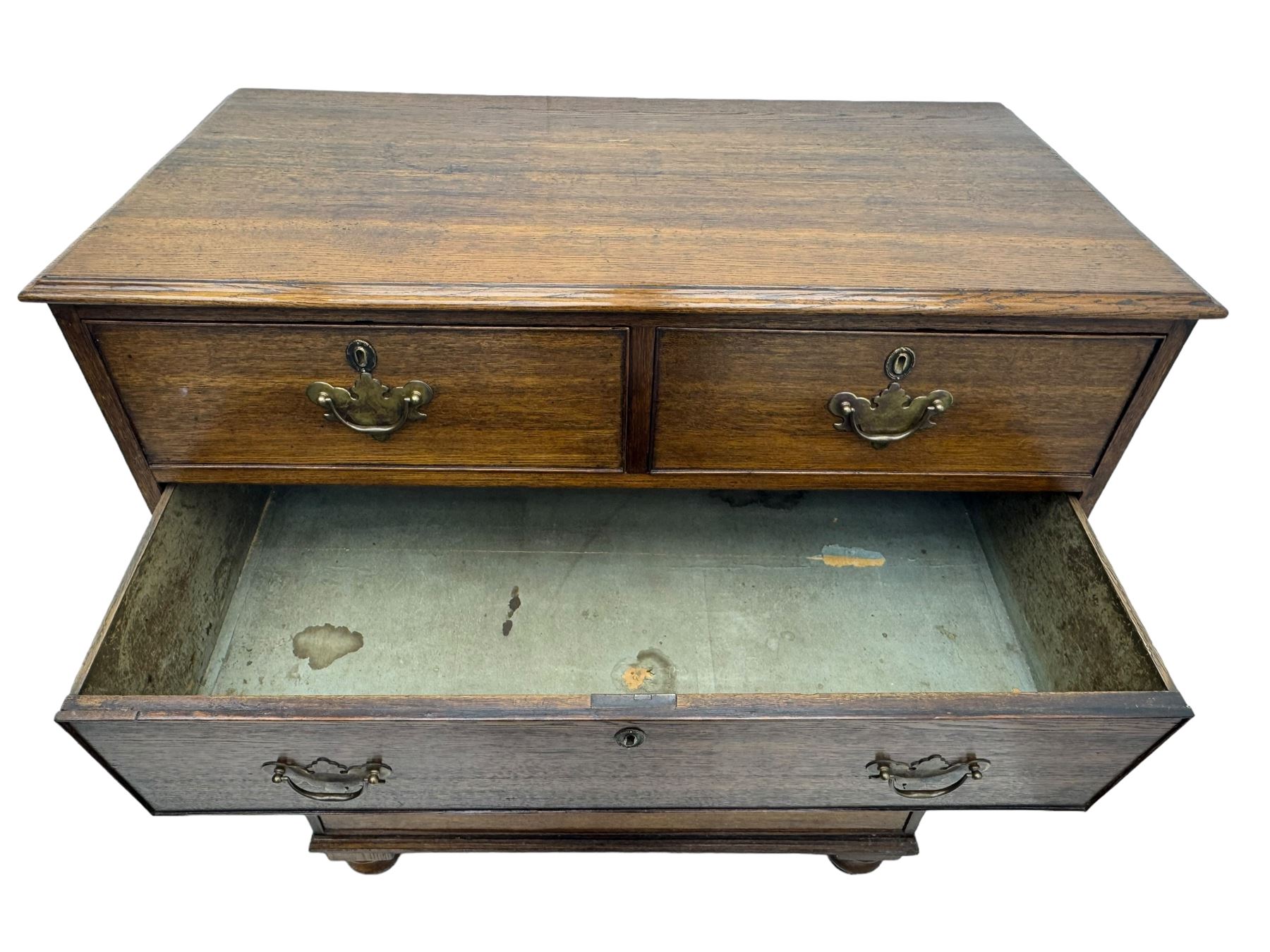 George III oak chest, rectangular top with moulded edge over two short and three long graduated drawers, each with brass escutcheons and shaped backplate handles, on turned bun supports 