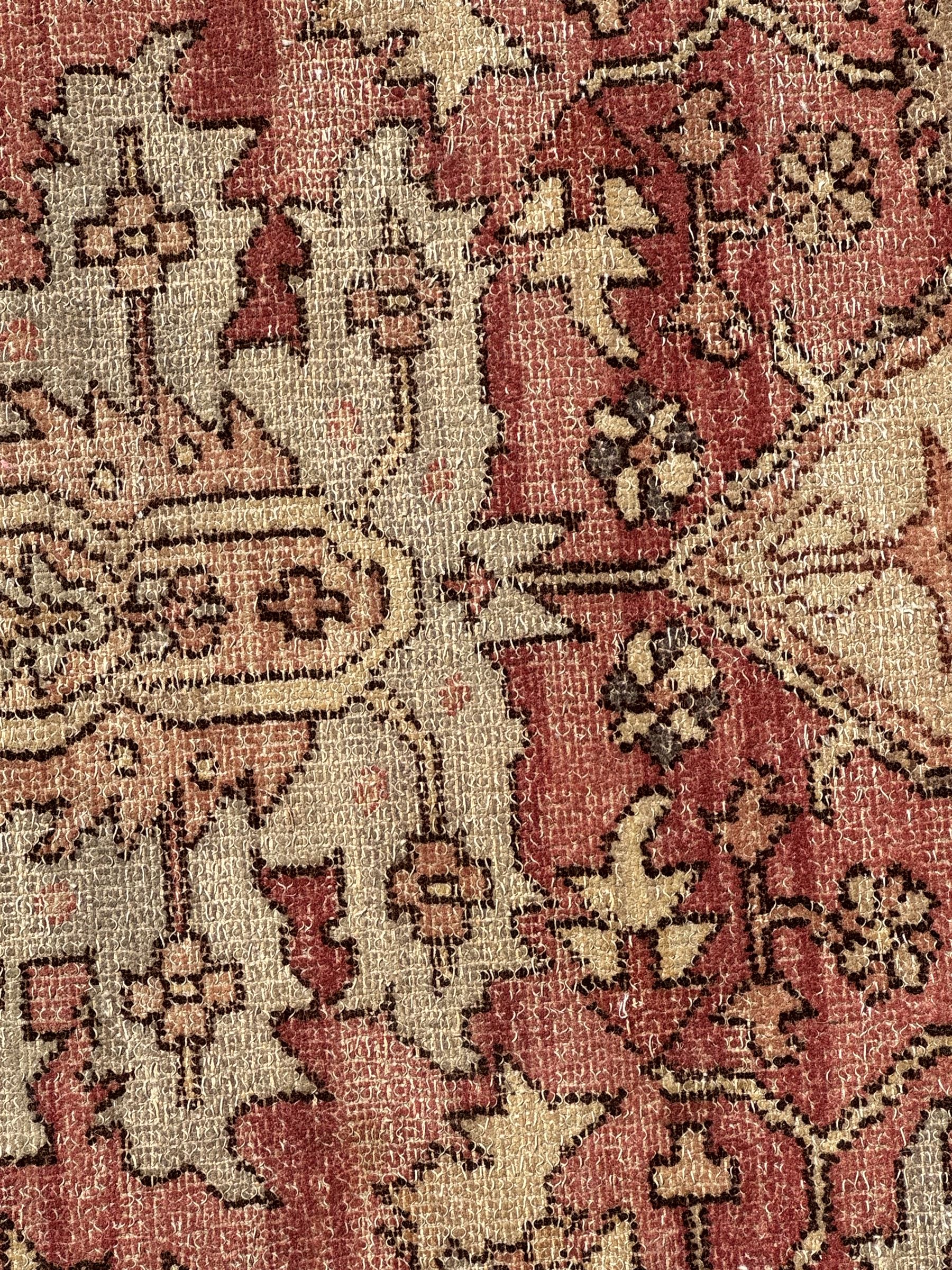 Persian Heriz design rug with red ground, the field featuring a central medallion with floral and geometric motifs, surrounded by ivory spandrels, the main border showcasing a series of floral patterns on a dark blue ground