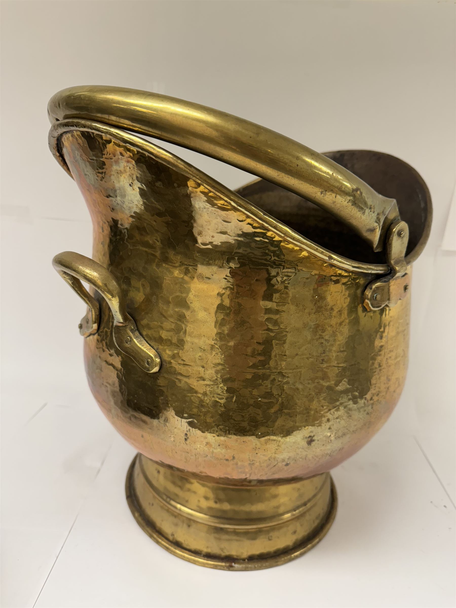 Middle eastern copper bucket, with chased and embossed band of animal decoration, together with a copper jardinière embossed with floral panels, copper plate with embossed leaf motif and two brass helmet shaped coal scuttles, bucket H26cm