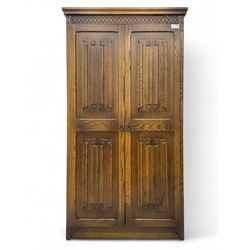 Jacobean design oak double wardrobe, projecting cornice over Gothic arched tracery carved frieze, twin panelled doors with linenfold relief carved detailing, on plinth base