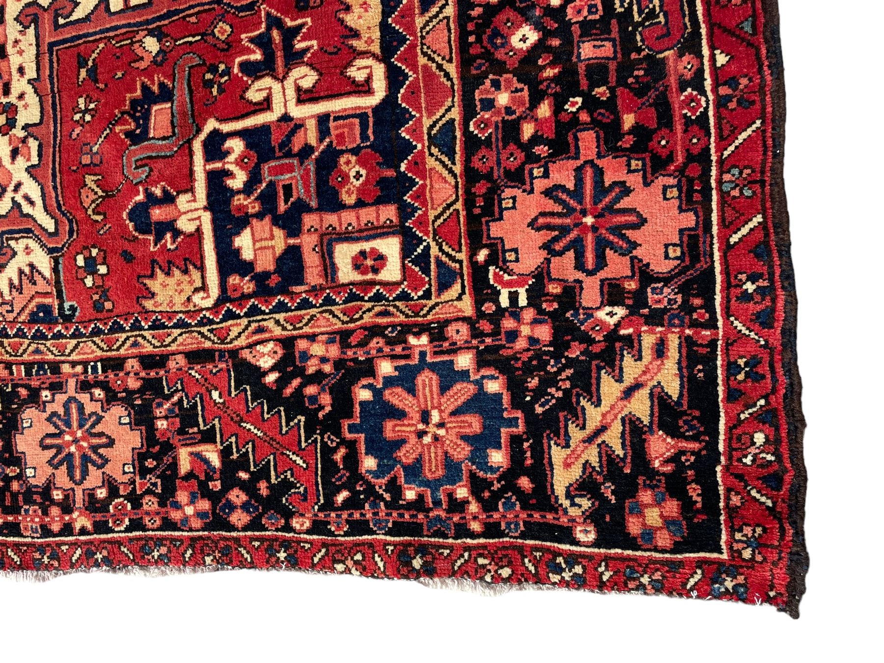 Persian Heriz red ground carpet, large central eight point medallion with projecting palmettes surrounded by small geometric motifs, decorated profusely with hooks, rosettes and animals, the busy border decorated with stylised foliate motifs within guard stripes 