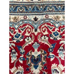 Persian Kashan crimson rug, central cusped medallion surrounded by interlacing branches decorated with leaves and palmettes, ivory ground spandrels and border decorated with scrolling branches and stylised plant motifs, within guard stripes  