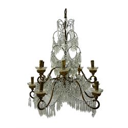 India Jane Interiors - pair of contemporary gilt bronze and crystal chandeliers, the framework featuring scrolling arms and garlands of crystal beads, each with twelve candle-style light fixtures with scalloped glass bobeches, adorned with multiple tiers of cut glass prisms, terminating in a central finial with a suspension loop