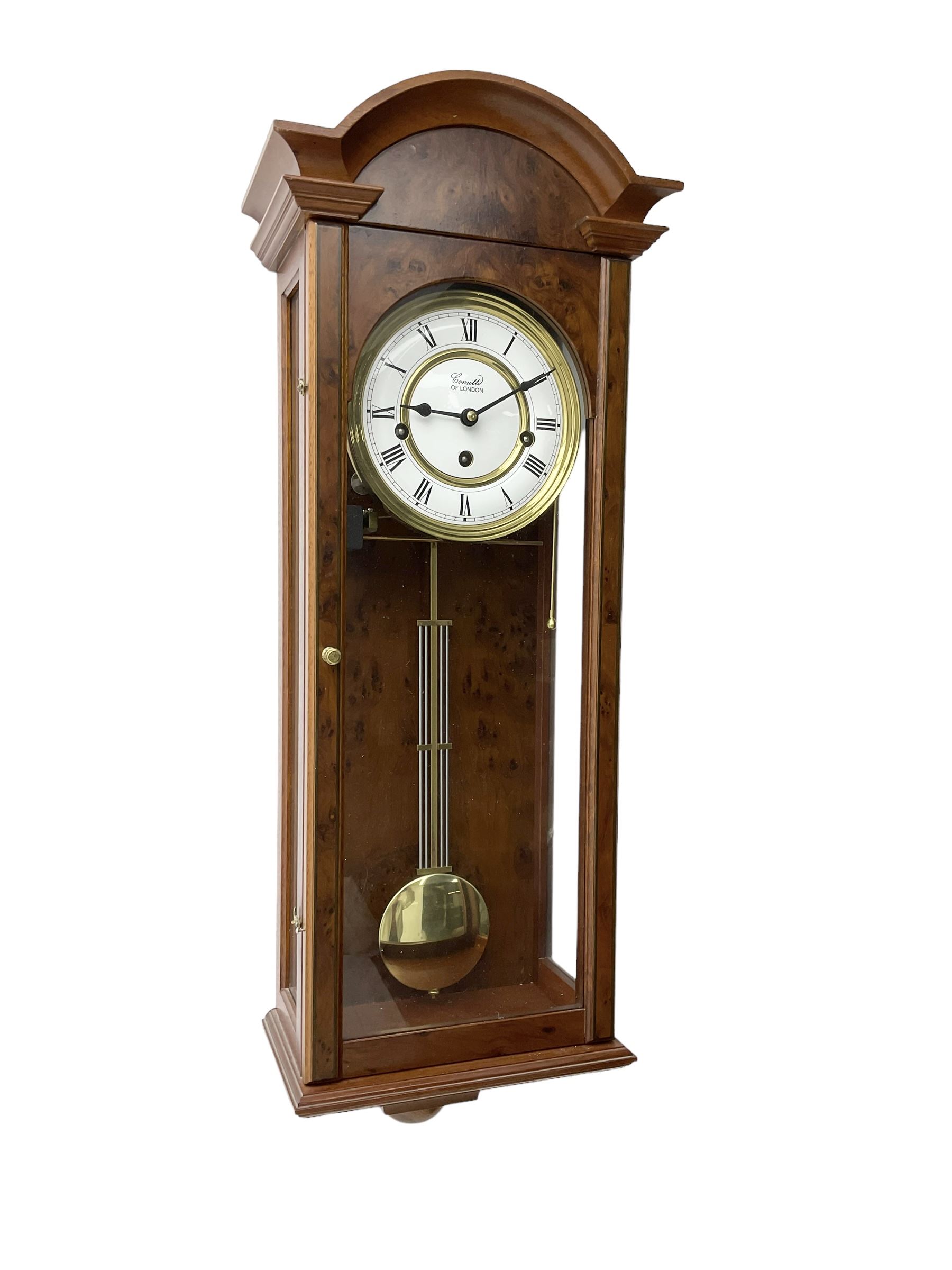 Comitti,  London - 20th century 8-day chiming wall clock in a walnut case, with a moulded break-arch top and full length glazed door and side panels, two part enamel dial with spade hands and visible gridiron pendulum, three train spring driven movement chiming the quarters on 5 gong rods.