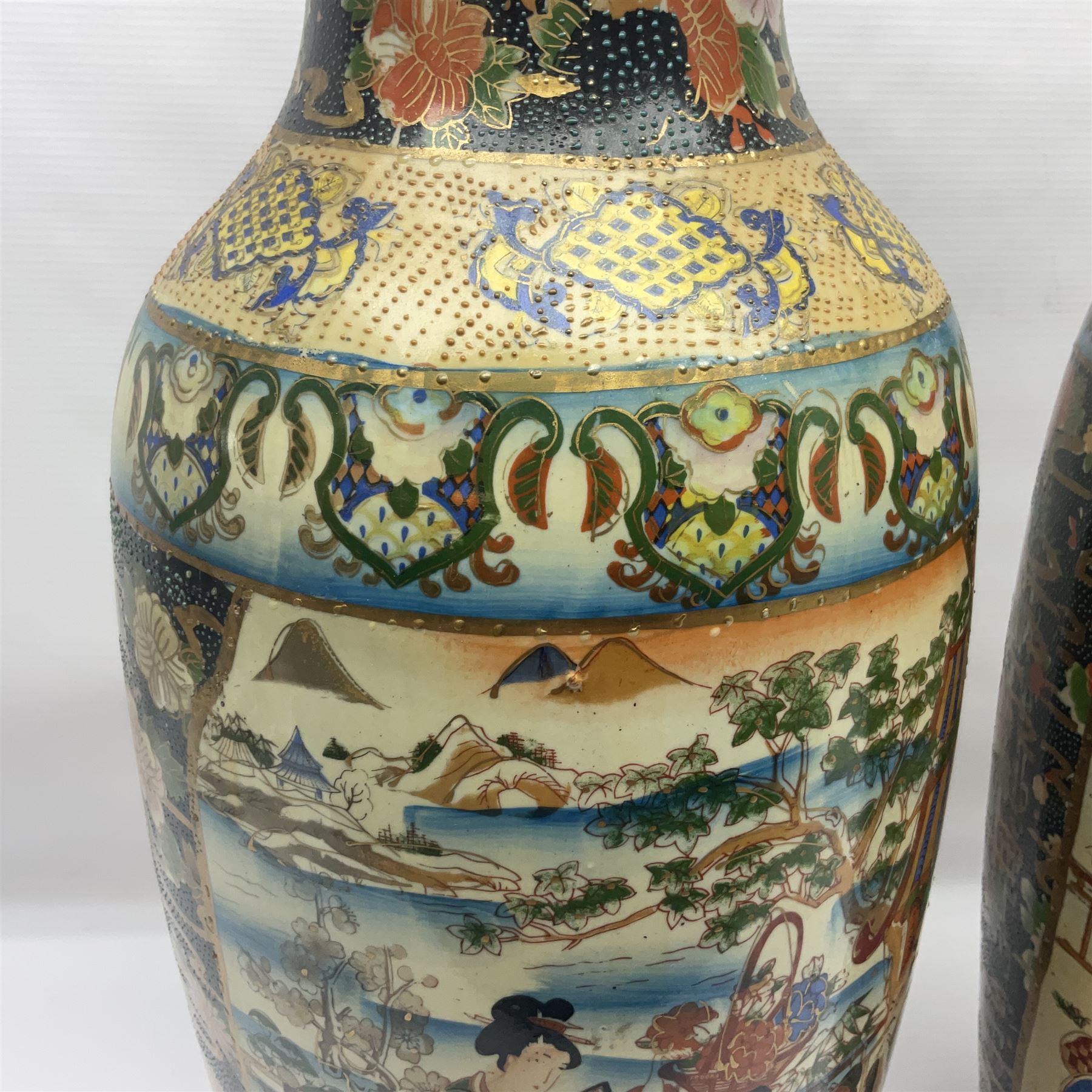 Pair of modern Satsuma vases of baluster form, decorated with figures in within river landscapes and floral borders, highlighted in gilt, H60cm