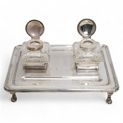 George V silver inkstand of rectangular design with pen tray and two cushion shape glass inkwells with silver covers, raised edge and four shaped supports 28cm x 20cm Birmingham 1912 Maker William Hutton & Sons