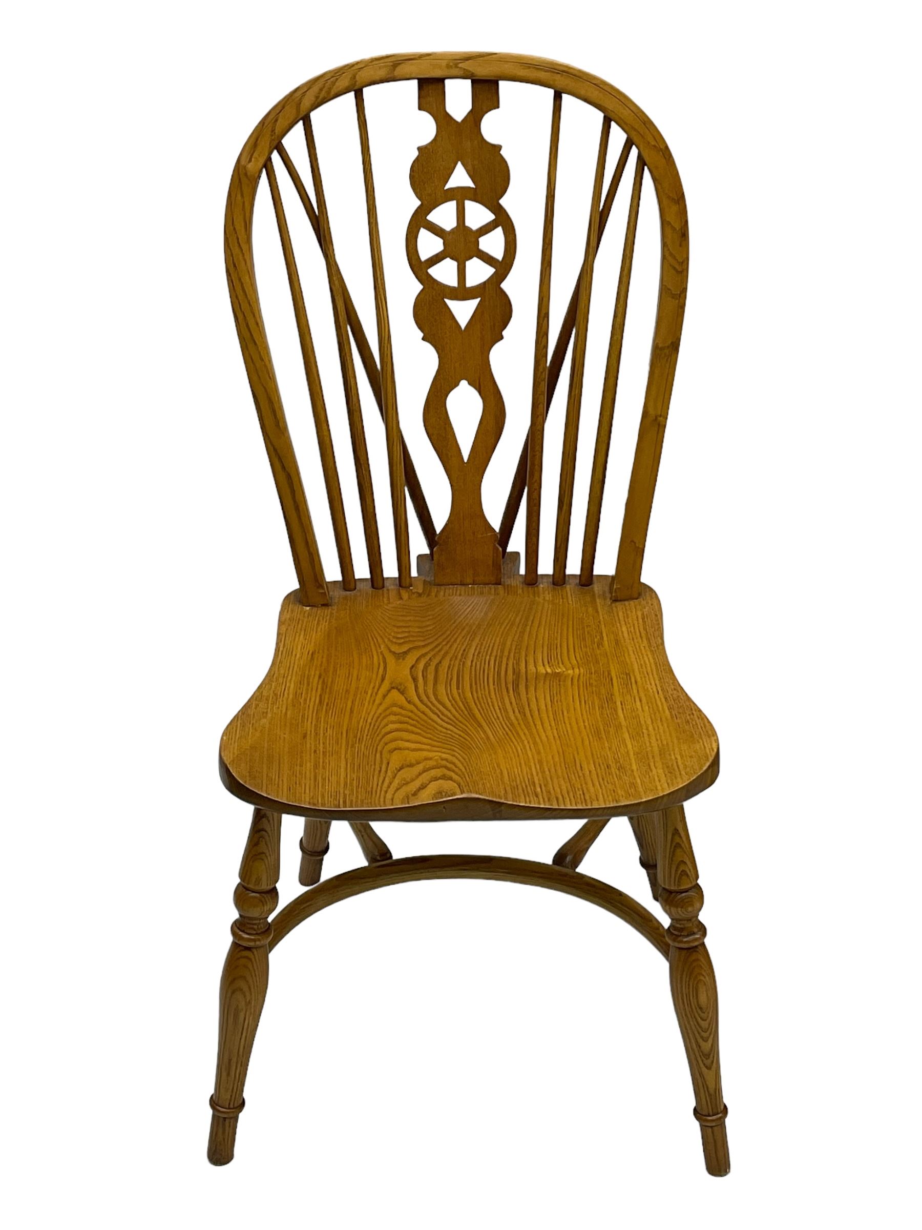 Set of four elm Windsor dining chairs, hoop and stick back with shaped wheel splat, dished seat on turned supports united by crinoline stretcher 