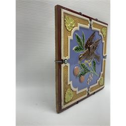 19th century Minton & Co majolica tile, decorated in relief with a bird upon a fruiting branch against a blue ground, with textured ochre border and anthemion to each corner, impressed mark verso, H19.7cm