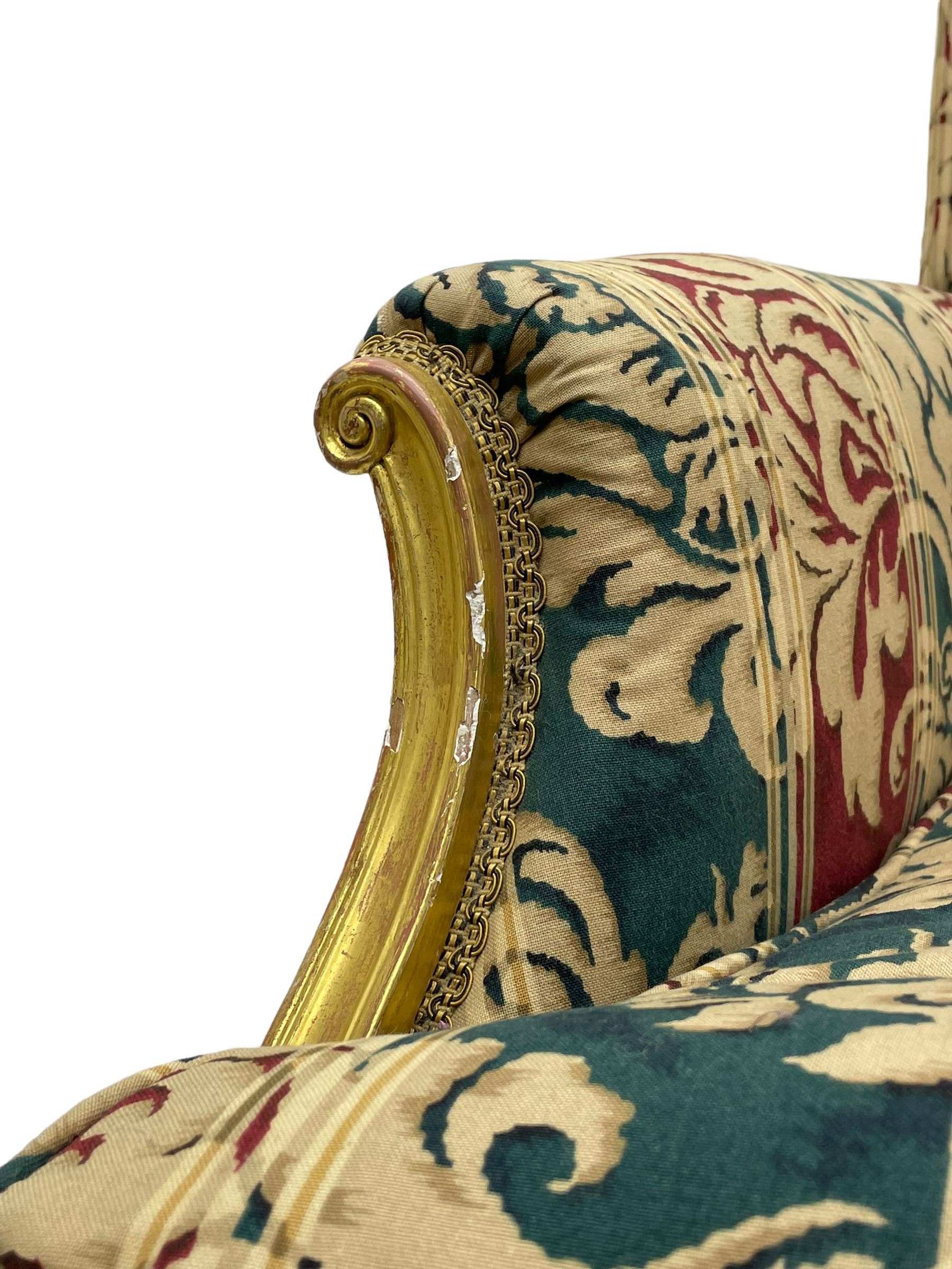 William Bertram & Son of London - pair late 19th century giltwood armchairs, moulded frame with scroll carved back and arm terminals, upholstered in striped fabric with foliate pattern, on shell carved cabriole supports, the brass castors stamped 