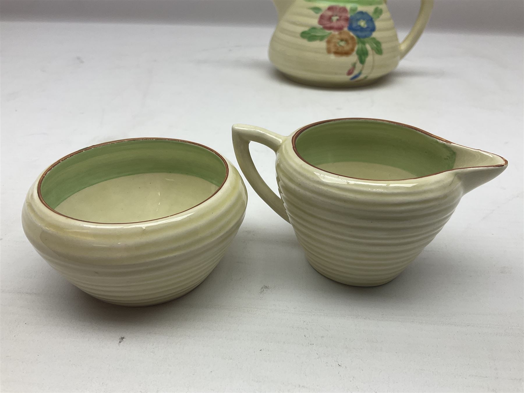 Clarice Cliff for Newport Pottery three piece tea service, in Nosegay pattern, comprising teapot, milk jug and sugar bowl, with printed mark beneath, teapot H12.5cm