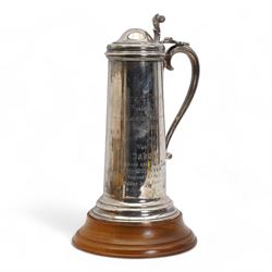 'Tennent Trophy presented by Tennent Caledonian Breweries, Scotland, Ayr 21st July 1975, won by Dakota owned and bred by Mr Guy Reed, trained by Sam Hall, ridden by A Barclay' - A tall lidded tankard with scroll thumbpiece and handle, on a wooden plinth H35cm overall London 1975 Maker Garrard & Co. Ltd