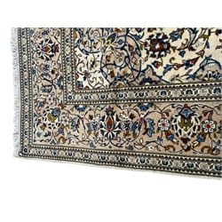 Persian Kashan ivory ground rug, central floral medallion surrounded by interlacing leafy branches and stylised plant motifs, scrolling spandrels, the border decorated with trailing branch and repeating palmettes, within floral pattern guard stripes 